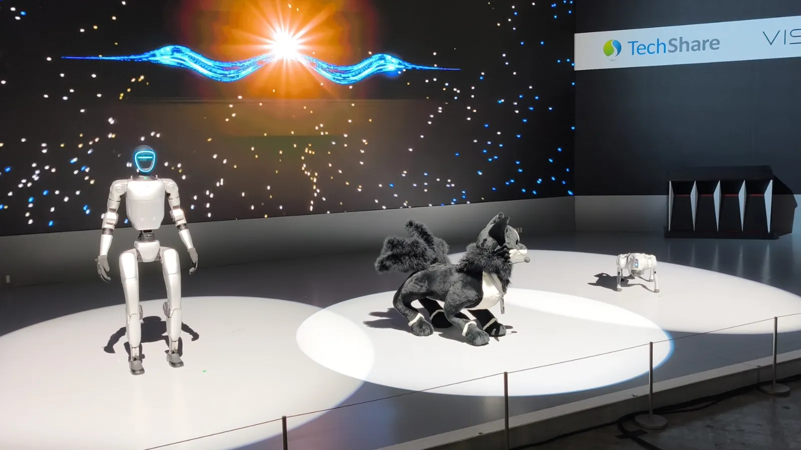 Un robot humanoïde blanc et un robot-chien sur une scène lumineuse, lors du Japan Mobility Show 2025