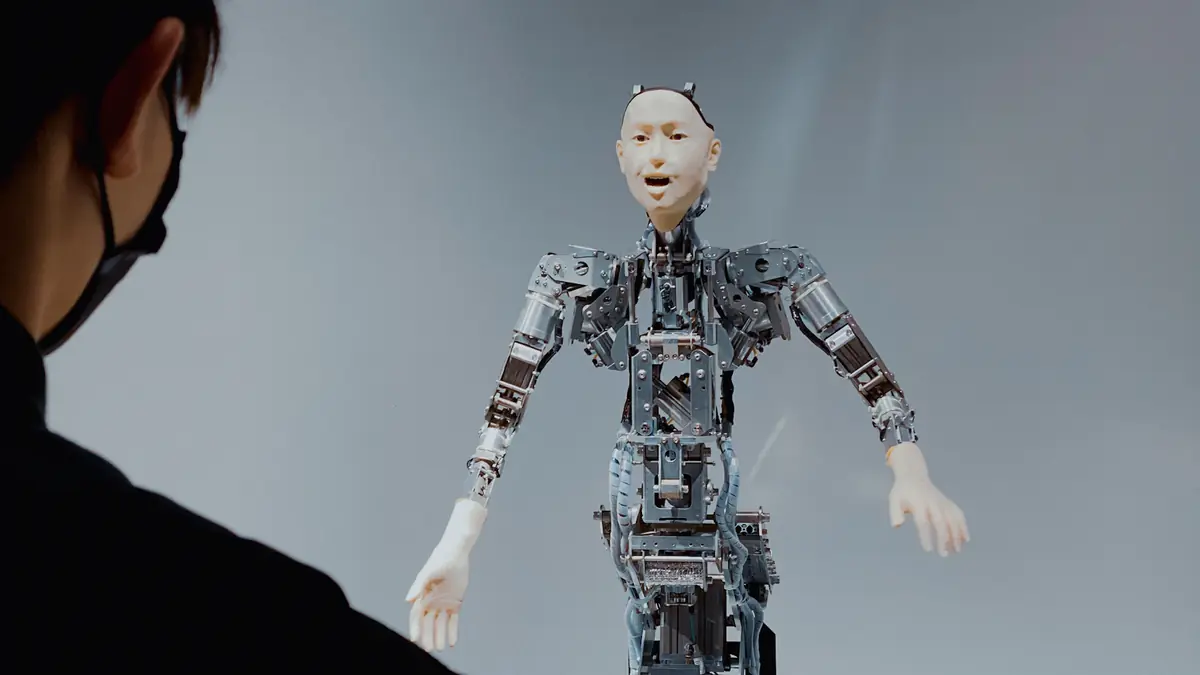 Un opérateur observe un robot humanoïde à l'ossature apparente, image de la téléopération
